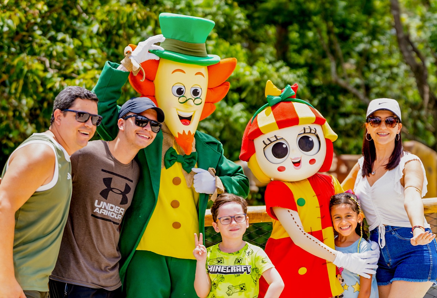 Família posando para foto com o Visconde de Sabugosa e a Emília durante a visita ao parque